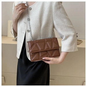Detail of dark brown crossbody bag with geometric quilting and silver chain strap