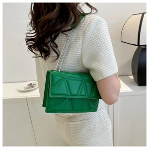 Detail of bright green quilted shoulder bag with silver chain strap on light outfit