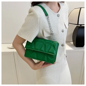 Detail of green quilted crossbody bag with silver chain strap shown in a lifestyle setting