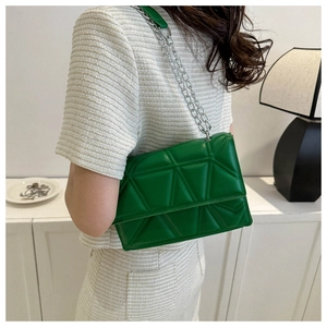 Close-up of green quilted bag with triangular patterns and silver chain strap details