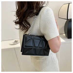 Modern black quilted crossbody bag with silver chain strap shown on model's shoulder