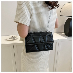 Detail shot of black quilted shoulder bag with silver chain strap on model shoulder