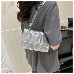 Detail of silver metallic quilted handbag featuring geometric patterns and chain strap