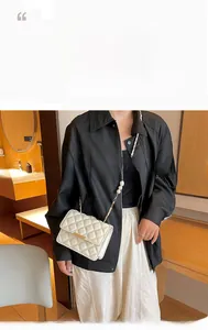 Gros plan sur sac blanc matelassé avec bandoulière en perles et chaîne métal doré