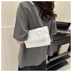 Detail of pearl white chain crossbody bag showing geometric quilted pattern and silver strap