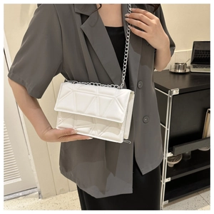 Close-up of a white quilted crossbody bag with geometric triangle stitching and chain strap