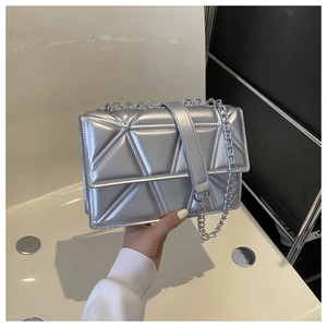 Detail of silver crossbody bag featuring geometric triangle stitching and metal chain