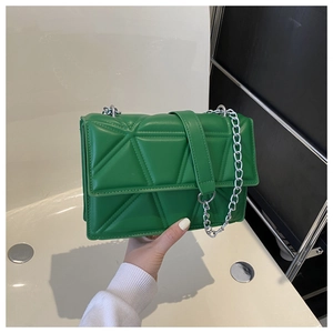 Detail of green quilted crossbody bag with silver chain strap and triangular stitching