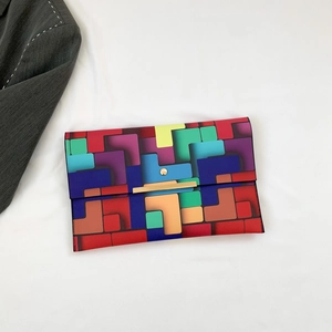 Bunte geometrische Umschlag-Clutch-Tasche mit goldenem Metallverschluss auf weißem Stoff