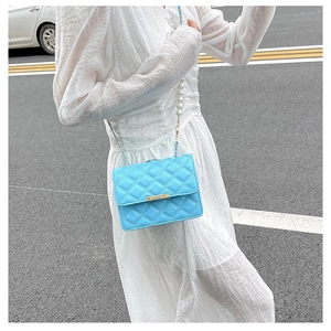 Détail d'un petit sac bleu vif matelassé avec chaîne en perles et métal doré