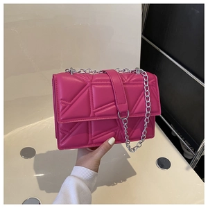 Detail of magenta quilted crossbody bag with silver chain and geometric diamond stitching