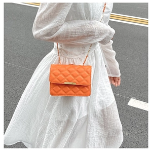 Détail du sac à bandoulière matelassé orange avec fermoir doré et bandoulière chaîne