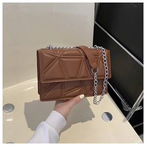 Detail of caramel brown crossbody bag with geometric quilting and silver chain strap