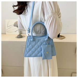 Detail of light blue quilted handbag with matching small pouch on white dress model