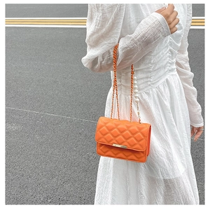 Détail du sac orange à matelassage avec bandoulière dorée et poignée en perles