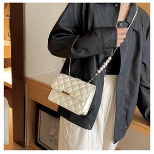 Détail du sac bandoulière matelassé blanc cassé avec chaîne en perles et boucle dorée