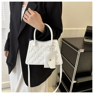 Close-up of white quilted handbag with M-pattern texture and detachable mini envelope pouch