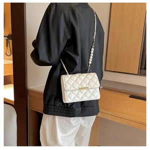 Détail du sac bandoulière blanc matelassé avec chaîne dorée et perles fantaisie