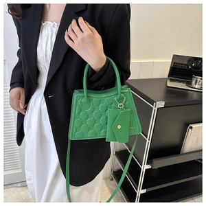 Detail of green quilted crossbody bag with matching mini pouch and top handle