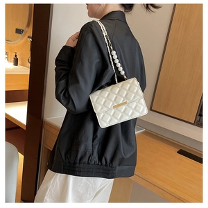 Gros plan sur un sac bandoulière blanc matelassé avec chaîne en métal et perles chics