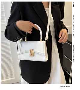 Detailed view of white crossbody bag with gold lock and textured braided handle