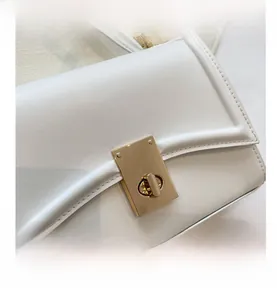Close-up of white leather handbag with golden rectangular twist lock and fine stitching