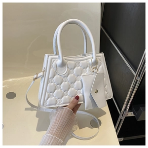 Macro shot of white quilted tote bag with embossed textures and a mini envelope pouch