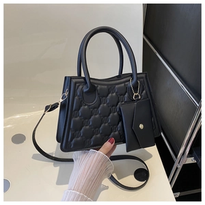 Detail of quilted black handbag featuring a mini envelope charm and gold button accents