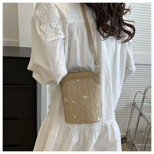Detailed back view of a woven bucket bag with floral embroidery and long leather strap