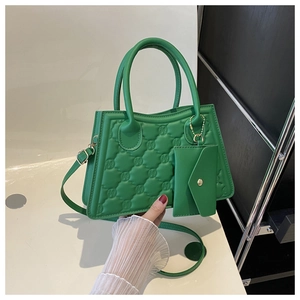 Detail of vibrant green quilted handbag with letter embossing and mini coin purse attachment