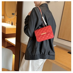 Détail du sac rouge matelassé avec fermoir doré et bandoulière en perles blanches