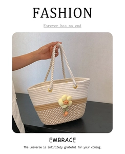 Détail du sac seau tissé avec design bicolore et accessoires de charme floraux