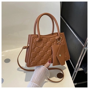 Detailed view of brown quilted handbag with letter embossing and matching small pouch