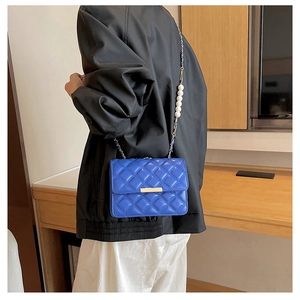 Détail du sac bandoulière matelassé bleu roi avec bandoulière de perles et de chaînes