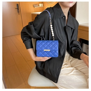 Détail du mini sac matelassé bleu avec chaîne à perles et boucle dorée