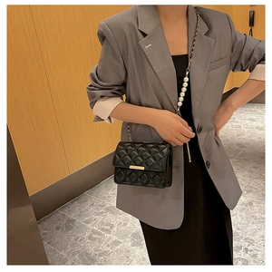 Détail du sac bandoulière matelassé noir avec chaîne en perles et métal élégante