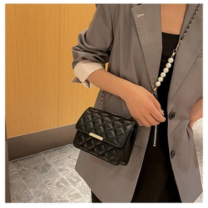 Détail du sac bandoulière matelassé noir avec chaîne en perles et boucle dorée chic