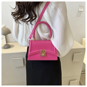 Detail of hot pink shoulder bag featuring a woven top handle and golden metal turn-lock