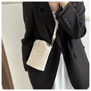 Detail of cream straw crossbody bag with floral embroidery and white leather strap