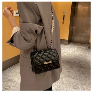 Détail du sac matelassé noir avec fermoir doré et bandoulière en perles blanches