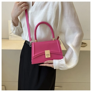 Detail of hot pink crossbody bag with gold twist lock on white shirt outfit