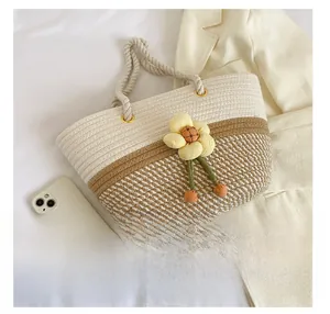 Détail d'un sac cabas tissé avec coutures contrastées et charme de fleur jaune