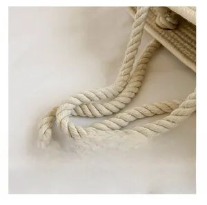Détail de la poignée en corde de coton sur un sac seau tissé beige pour l'été