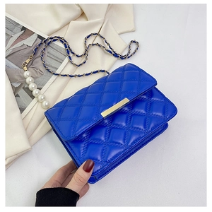 Détail du sac bandoulière matelassé bleu avec chaîne dorée et grandes perles blanches