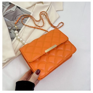 Détail du sac matelassé orange avec chaîne dorée et grandes perles décoratives