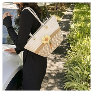 Détails de la texture du sac cabas tissé tricolore avec breloque fleurie jaune en extérieur