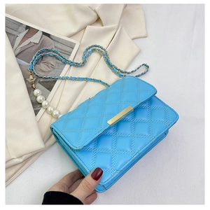 Détail du sac matelassé bleu clair avec chaîne en perles élégante et fermoir doré