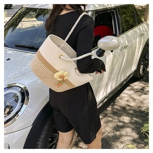 Détail du sac cabas en paille tissée avec pendentif tournesol et bandoulière en corde