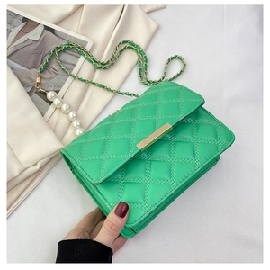 Détail du sac matelassé vert vif avec fermoir doré et bandoulière ornée de perles blanches