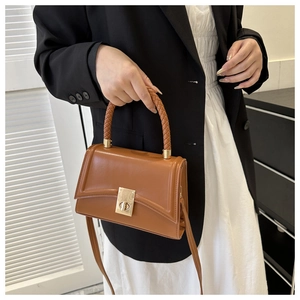Detailed side view of brown vintage satchel with woven handle and gold metal lock